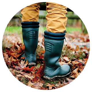 Person stood amongst autumn leaves, wearing a pair of Cotswold wellingtons