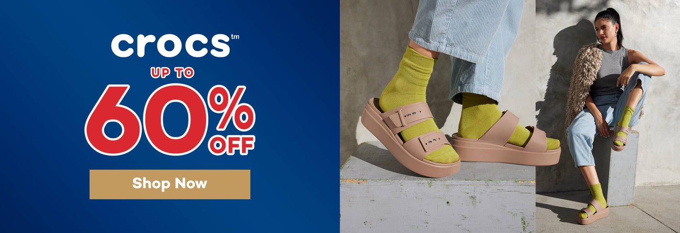 Advertisement for Crocs sale with up to 60% off and a person wearing Crocs Brooklyn Buckle sandals.